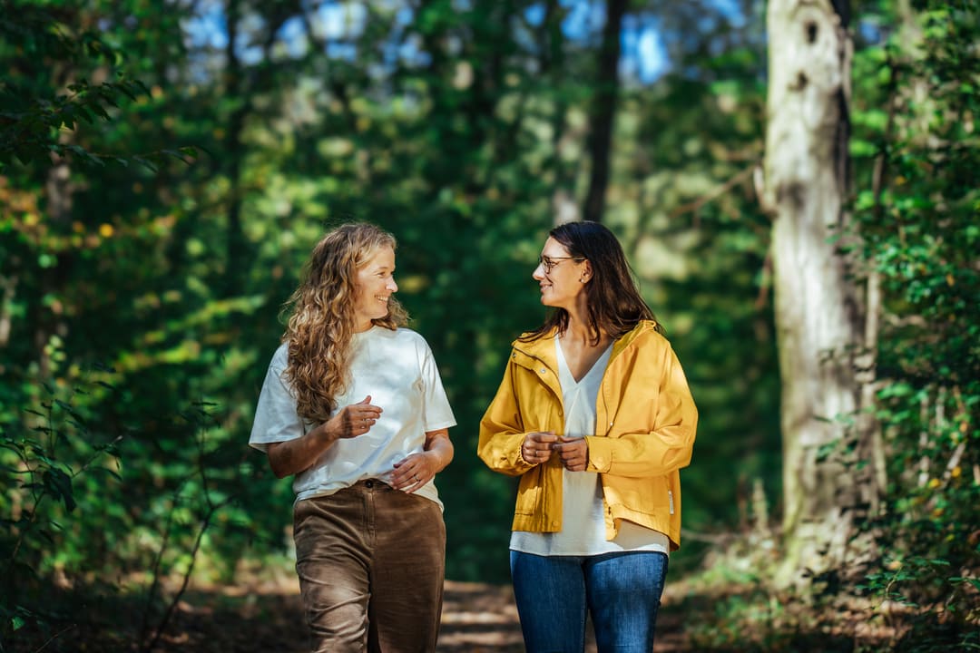 Angebote die aus der Reihe Tanzen Morgenspaziergang-2 Klientin & Coach beim Spaziergang im Wienerwald sitzen auf eine Bank